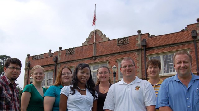 A group of interns stand in front of a brick building