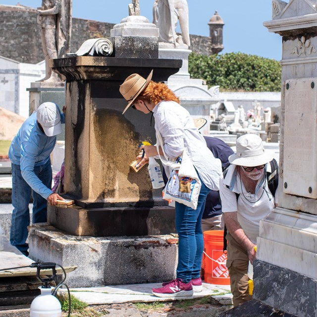 Two groups cleaning large grave monuments