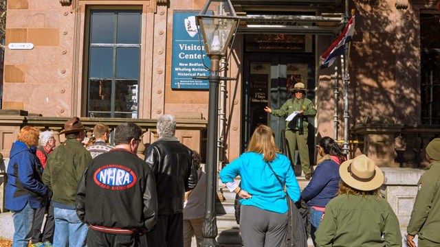 Large crowd standing in front of a ranger giving a tour
