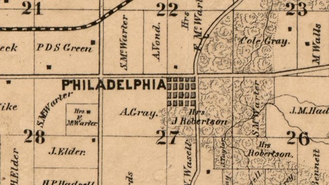 A historic map shows New Philadelphia at the corner of two roads. Town lots are organized in a grid.