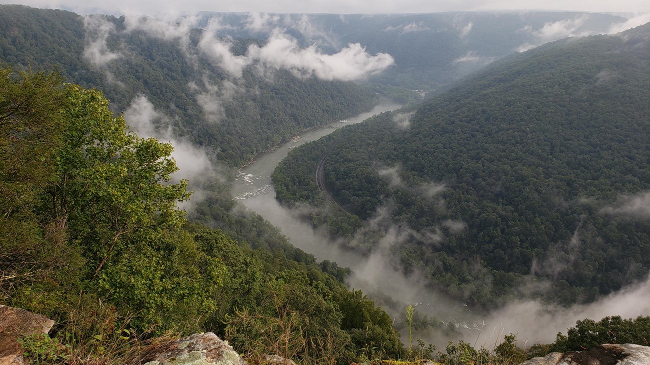 clouds over a deep, forested gorge and river