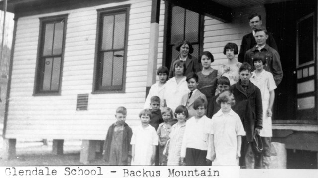 Black and white photo of a group of people in front of a school building