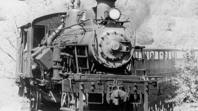 A black and white photo of a steam engine billowing smoke