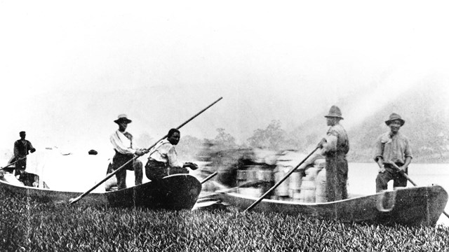 historic photo of men poling long, narrow boats on a river