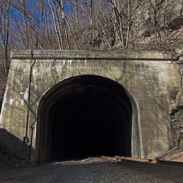 A cement railroad tunnel through a rocky mountainside