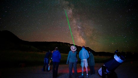 A park ranger uses a green laser to point out celestial features to visitors.
