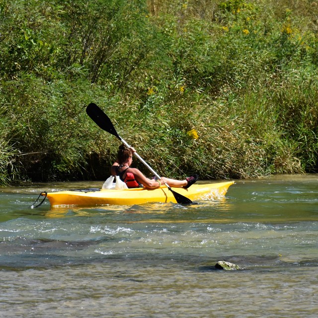 A woman in a yellow kayak paddles along the Niobrara NSR.