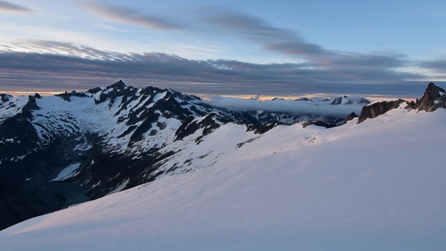 A snowy mountain range with clouds