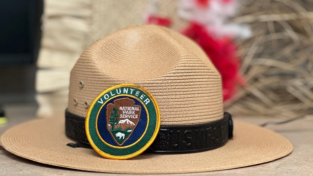 Indoors; Close up of a Ranger flat hat with sticker resting on brim.