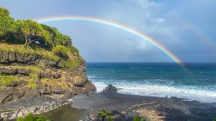 Double rainbow over the ocean near tall cliffs