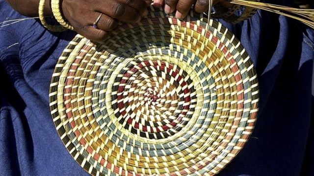 Hands weaving a circular basket