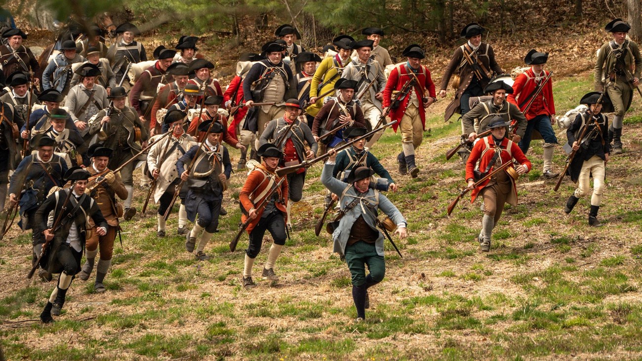 Reenactment of the Continental Army running through woods