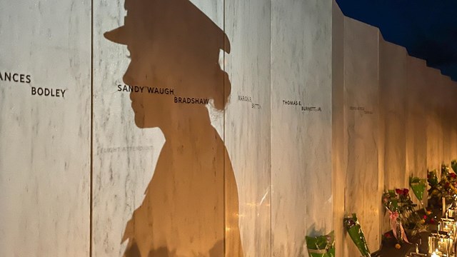 Silhouette of an office on a memorial wall lined with luminaries