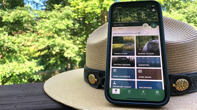 Smartphone displaying the NPS App learning on a park ranger hat