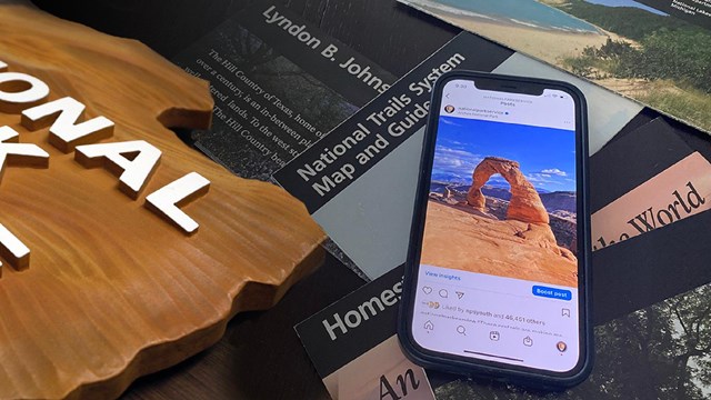 Smartphone displaying a social media post on top of the National Park Service logo