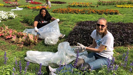 A few volunteers with garbage bags sitting in a flower garden