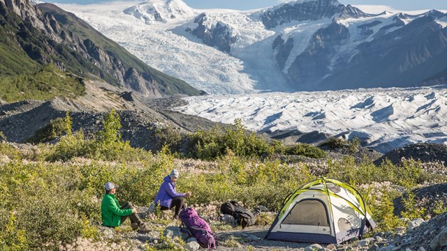 Two campers with tents near the base of a glacier