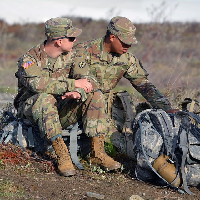 Two army soldiers sitting on ruck sacks