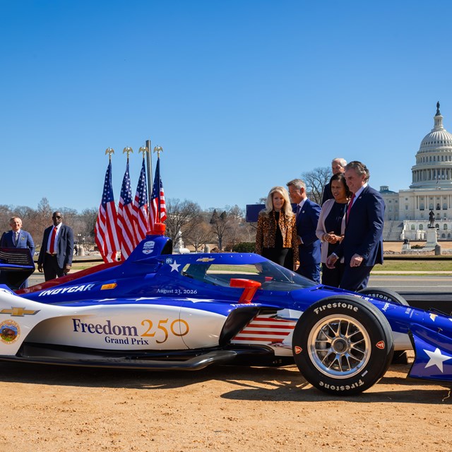 Indy car wrapped in a red, white, and blue graphic that reads Freedom 250 Grand Prix