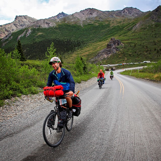 Group riding their bikes on a road near mountains 