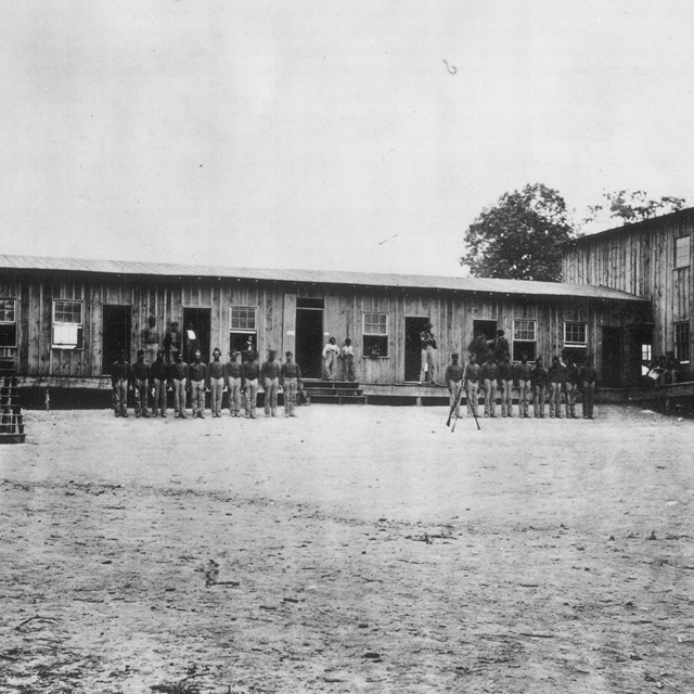 Historic image of a U.S. Colored Troops regiment in front of a military office