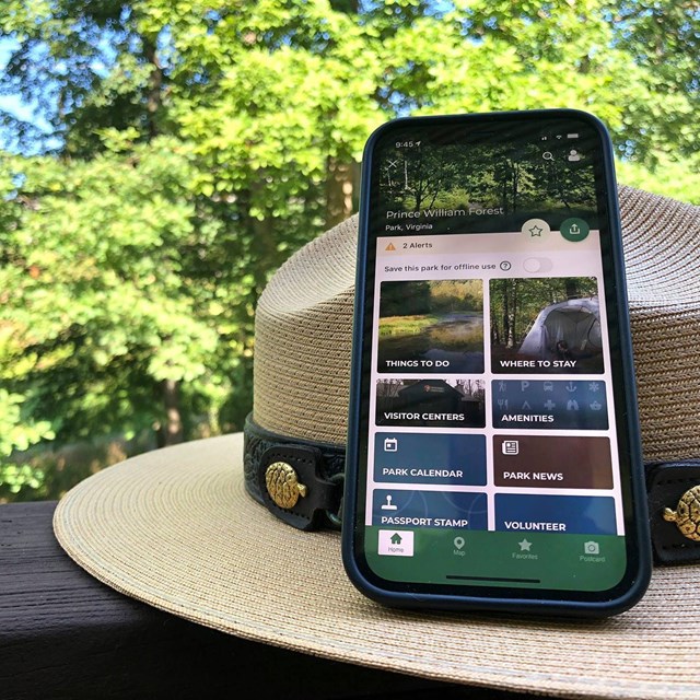 Smartphone displaying the NPS App learning on a park ranger hat
