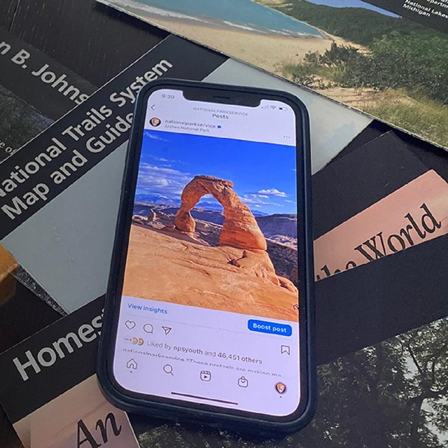 Smartphone displaying a social media post on top of the National Park Service logo