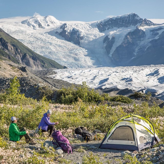 Two campers with tents near the base of a glacier