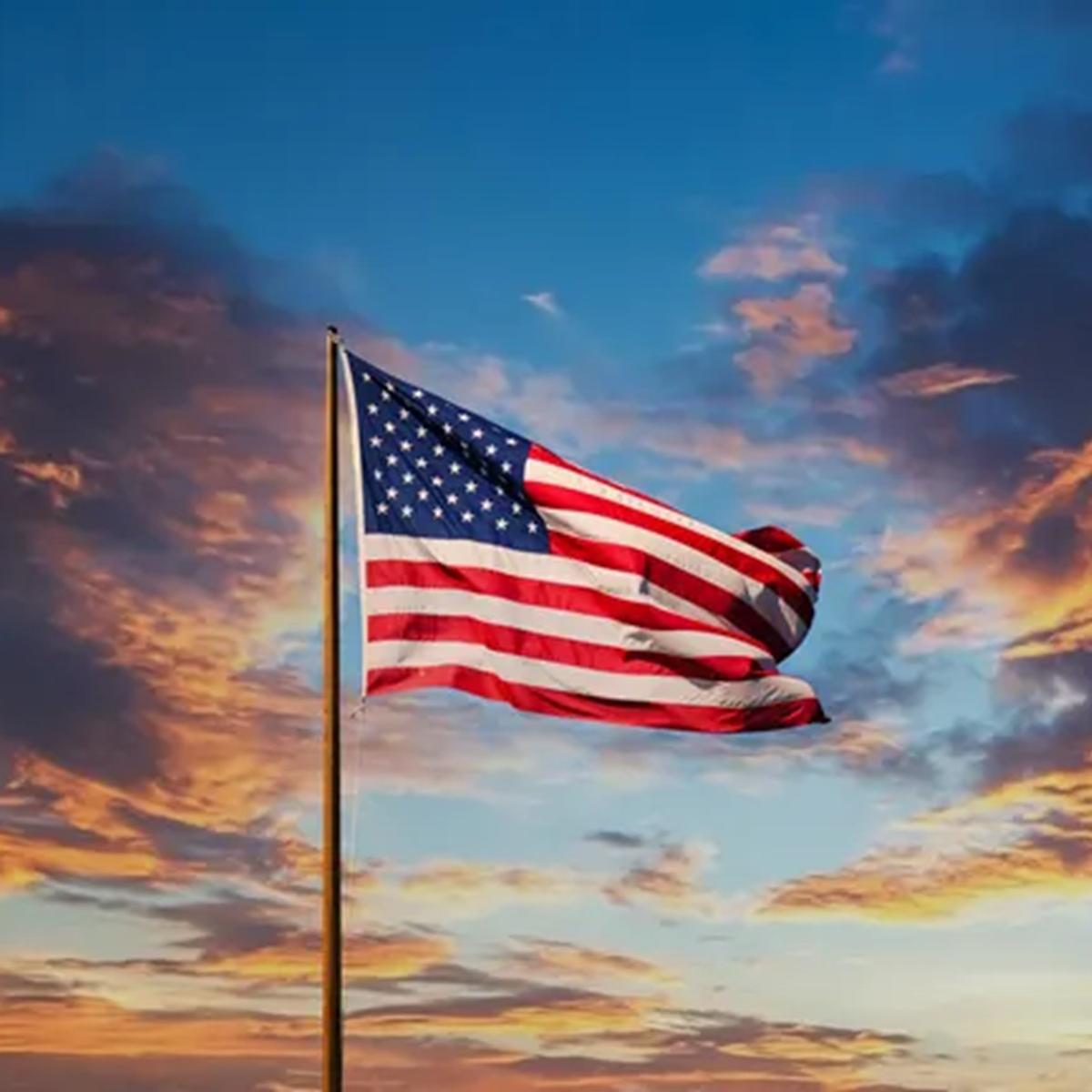 U.S. flag against a colorful sunset sky
