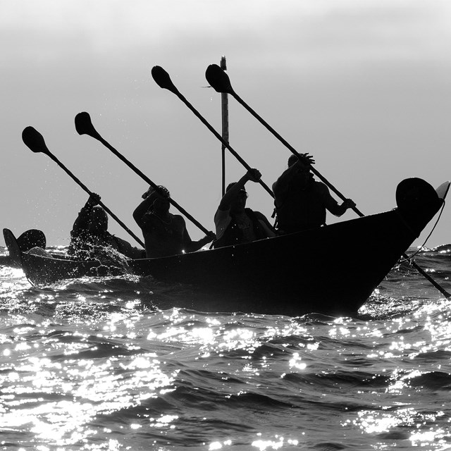 group of chumash paddling a traditional tomol on surface of the ocean