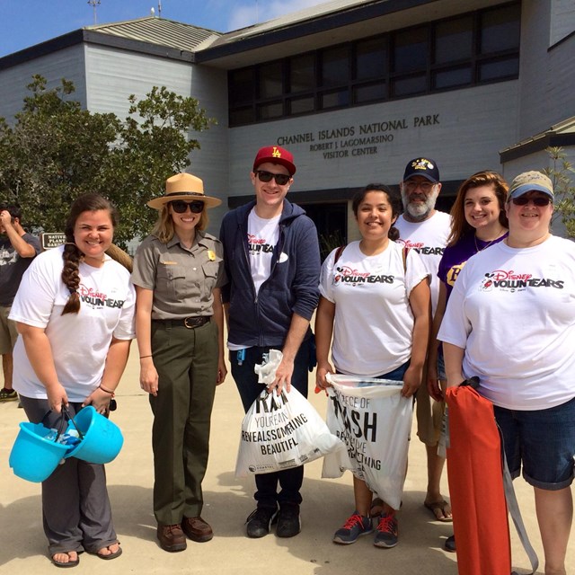 group of volunteers standing with a ranger, all holding bags of trash