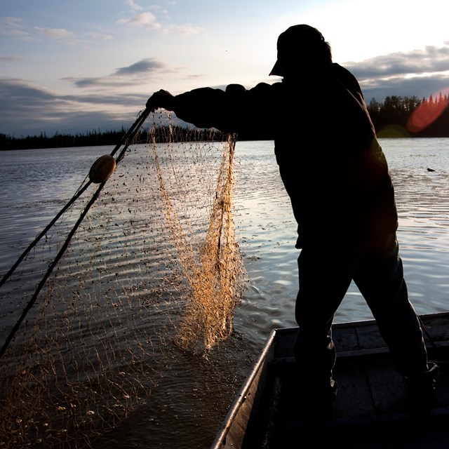 A man casts a net while fishing.