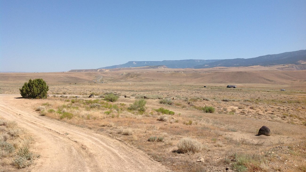 A dirt road that leads through a red-hued desert. 