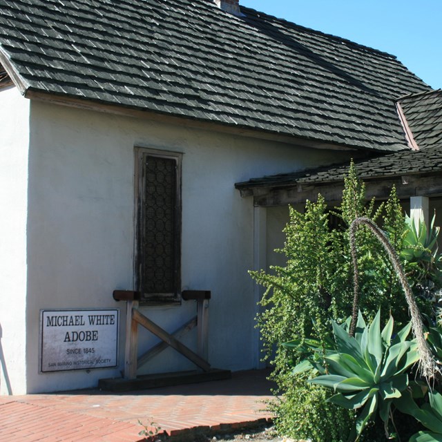 A small stucco house with a thatched roof.