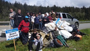 Volunteer group posing on beach with collected marine debris. 