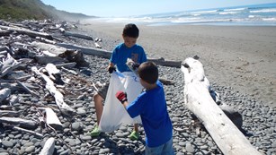 Young boys picking up marine debris on a beach.