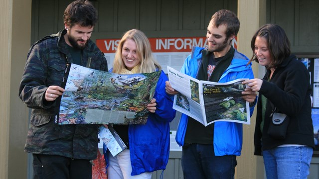 Visitors look at a newspaper in front of a visitor center