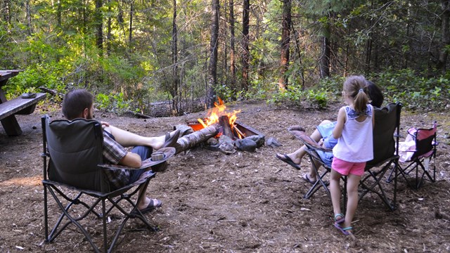 Three people sitting around a campfire at Caves Creek Campground.