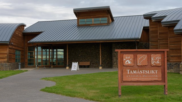 A large, one-story visitor center building front, with large entry doors.