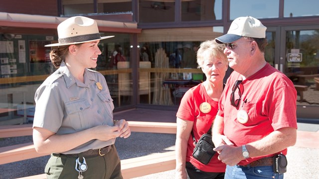 A ranger, in uniform, talking with two visitors