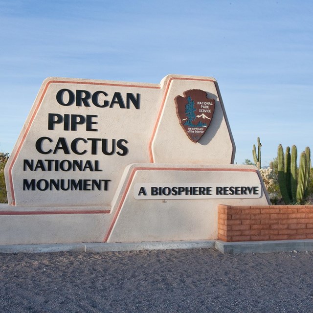 entrance sign to the monument, with NPS arrowhead and organ pipe cactus