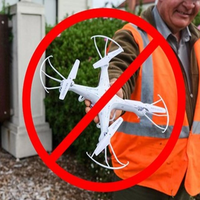 A park employee holds a drone with an x over it