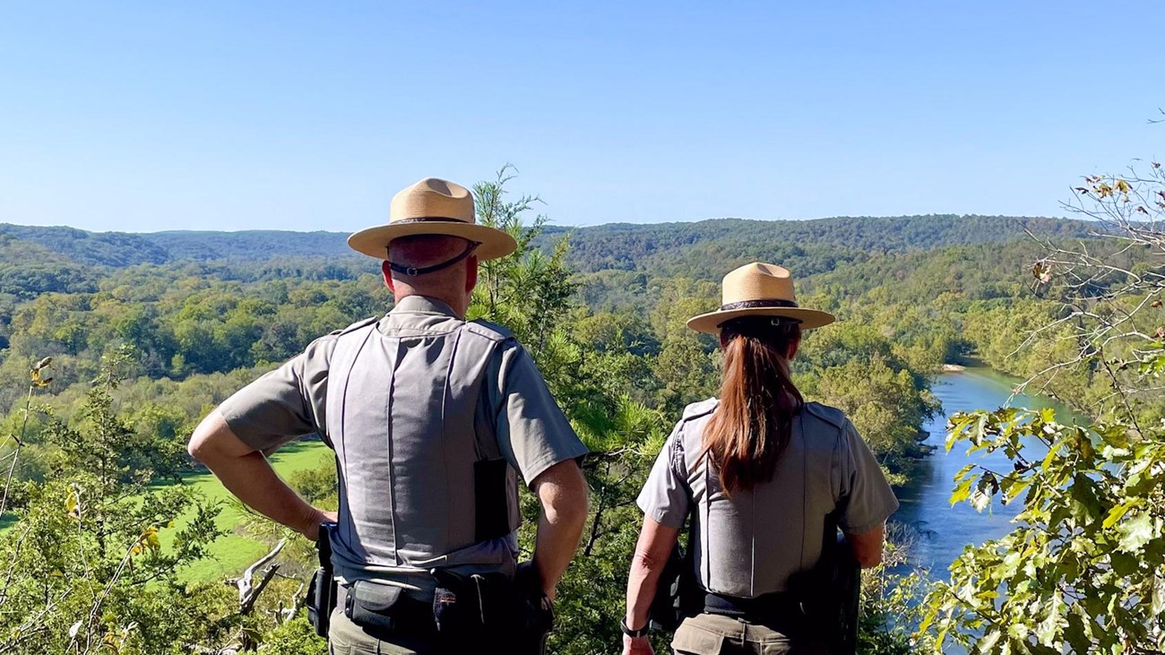 Two park rangers overlook a river.