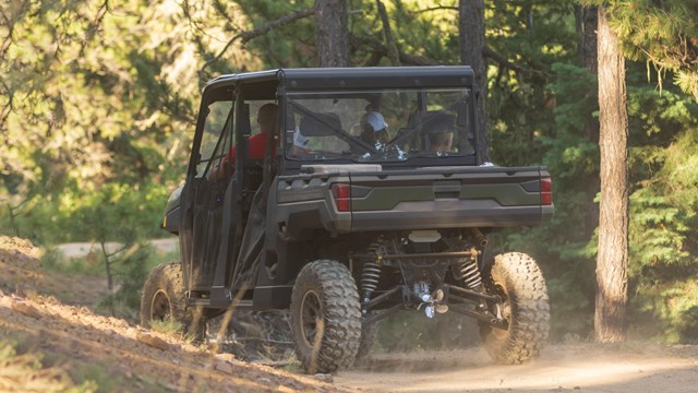 A side-by-side utility vehicle on a gravel road.