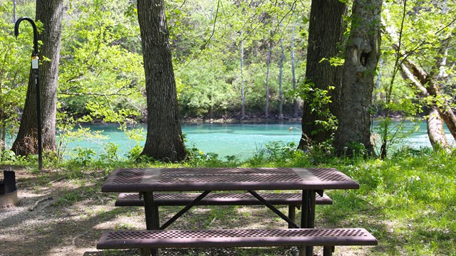 A picnic table sits along a beautiful blue river.