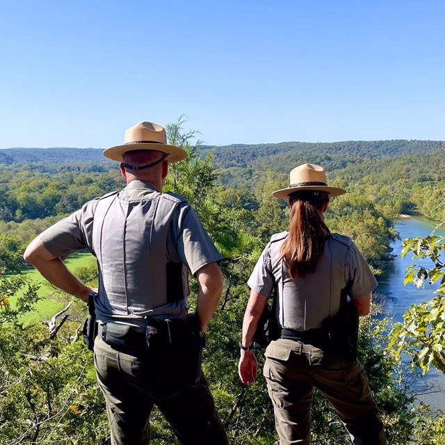 Two park rangers overlook a river.