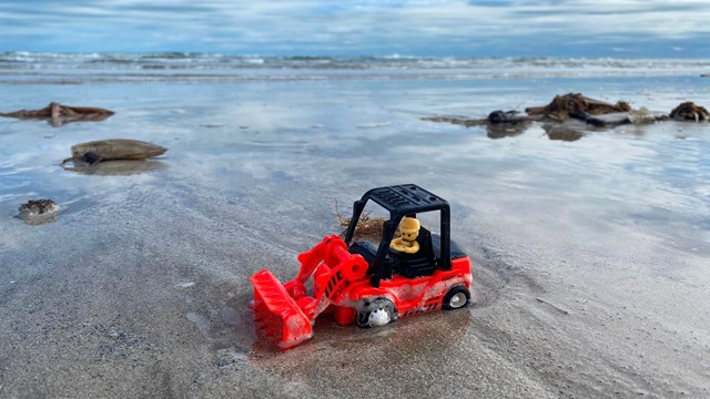 A toy truck on the beach.