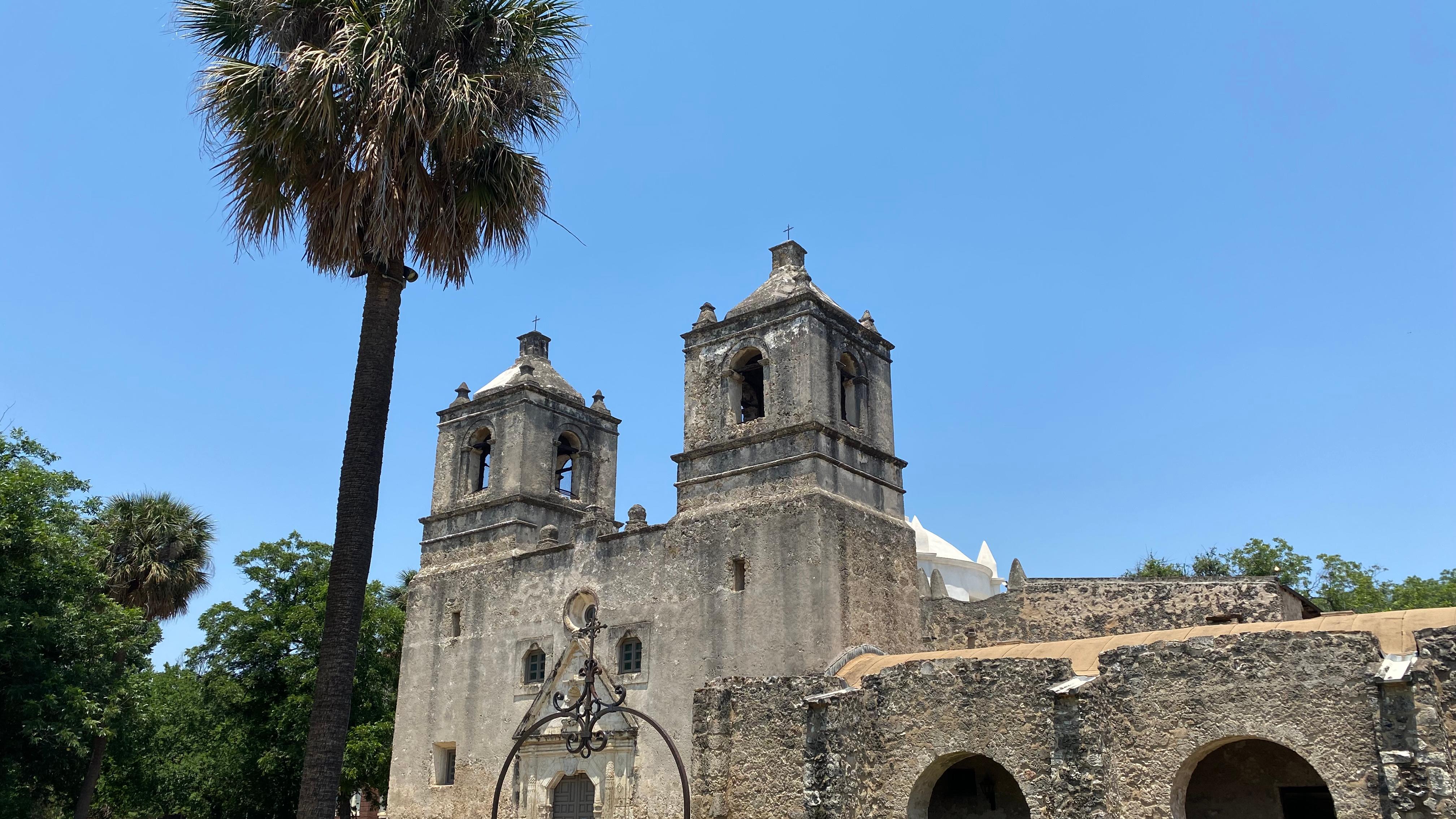 A historic Spanish mission with a palm tree in the front. 