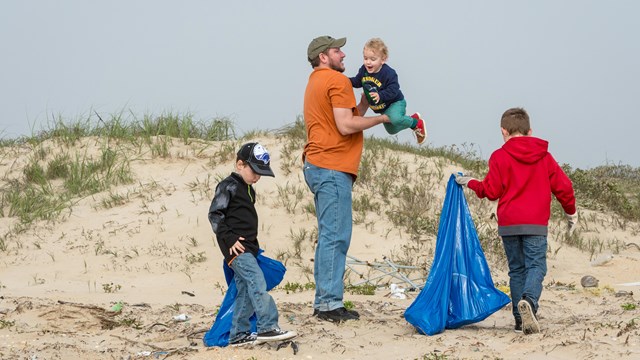 A family picks up trash on the beach.