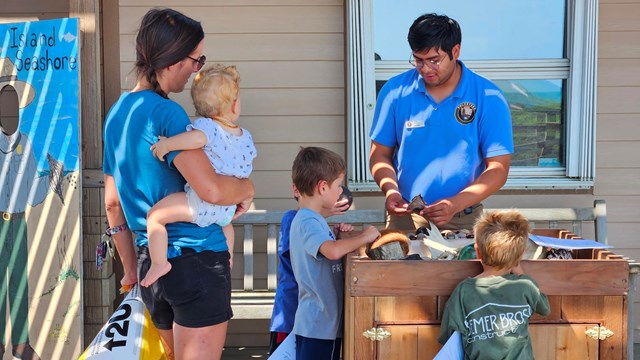 A park intern tell a group of children about shells that are found on the beach.